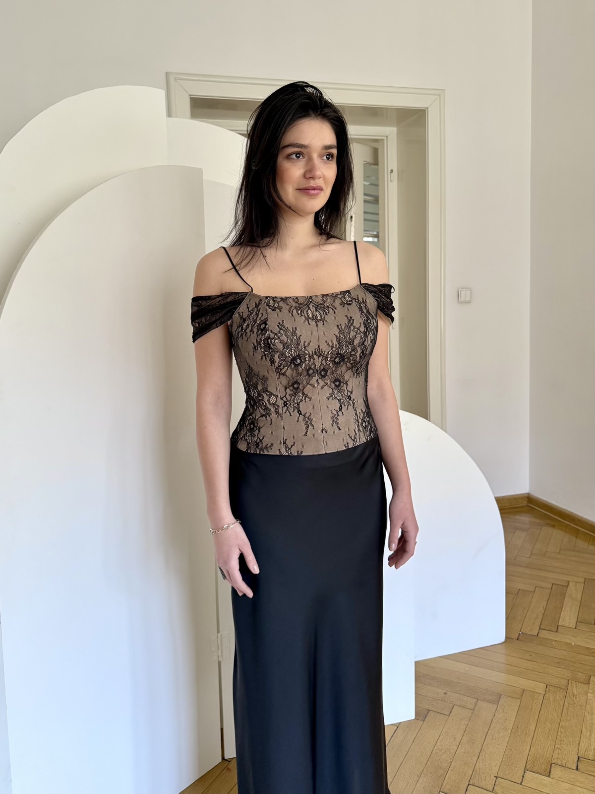 Corset din dantela neagra peste stofa nude, cu bretele cazute si fusta neagra.